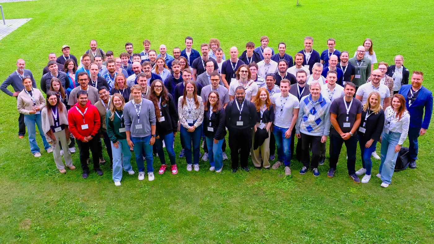 Group photo of roughly one hundred RL Bootcamp 2025 participants on a lawn at Universität Salzburg.